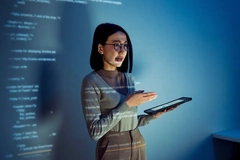 A woman holding an iPad with word projections across her face.