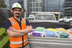 Image A person in a hard hat standing next to bags
