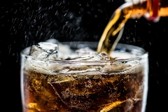Image bottle pouring soda into glass with ice