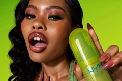 A woman holding a NYX fragrance.