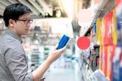 Image Asian man shopper choosing fizzy drink or carbonated soft drink in can package from shelf in supermarket