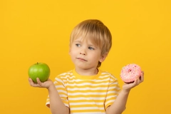 Image child holding up donut and apple