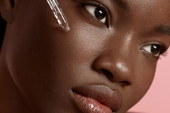 Woman applying cosmetics to face with serum pipette