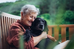 Older woman with dog sitting on terrace.