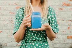 girl in green dress holding glass mug with blue drink