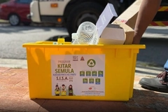 Image A hand moving a yellow recycling bin