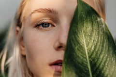 Image A woman with a leaf in front of her face.