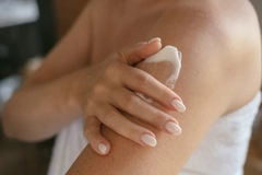 Image A woman rubbing cream on her skin.