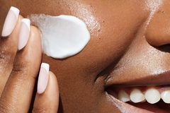 Image Black woman applying face cream.