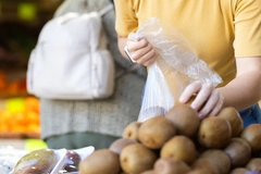 Image A person putting Kiwi in a bag
