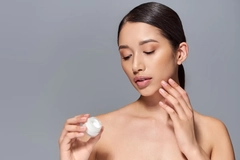Image A woman putting lotion on her face.