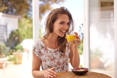 Image Woman eating cereal and drinking orange juice.