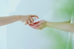 A hand getting sprayed by another.