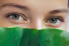 Image woman's eyes over top of large leaf