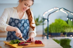 Image woman cutting beetroot and spinach leaves for organic raw salad on kitchen counter