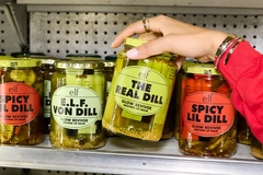 Image A hand reaching for ELF branded pickles.