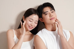 A man and woman smiling and touching their faces.