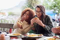 Image Friends eating burgers outdoors.