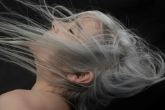 Image A woman with gray hair throwing her hair around.