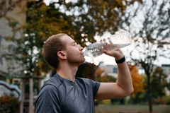 Image Young man drinking water after a workout in the park