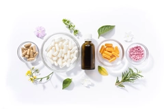 Different types of supplement pills in bowls and bottle with plants and flowers around