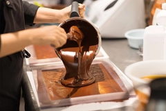 Confectioner filling mold with chocolate at confectioney shop.