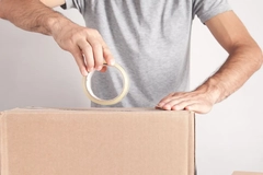 Image A person taping a carton box