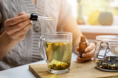 Close up of someone adding liquid using dropper into tea