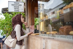 Image Muslim woman choosing pastries at coffee shop in Bali.