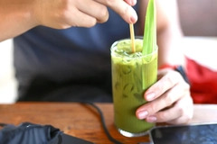 Image Person drinking pandan-based drink in glass.