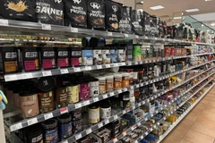 Several brands of whey protein powder on a grocery store shelf.