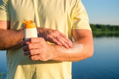 man puts sunscreen on arm 