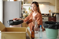 Image Young woman sorting waste and grouping into different categories at her kitchen table