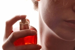Image A woman putting perfume on her neck.
