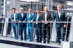 Corporate men line up in factory to take photo