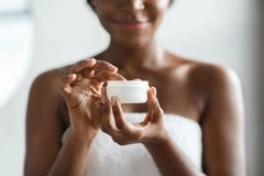 Image woman holding tub of skin cream