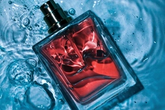 Image A perfume bottle with orange liquid on top of water.