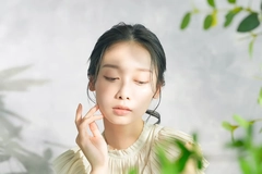 Image A woman with plants in front of her face.