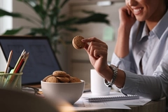 Image Female worker having cookies for a snack in the office.