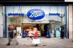 Image The outside of a Boots store with people walking by.