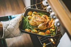 Image Cook taking ready chicken from the oven.