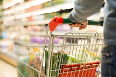 A person pushing a grocery cart through a store.