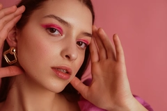 Image A woman wearing makeup and holding her face.