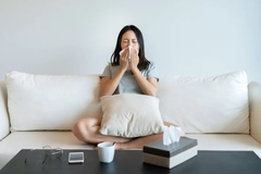 Image Sick woman on sofa blows her nose