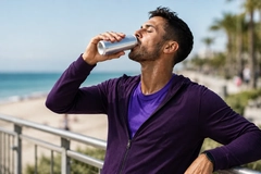 Image man drinking from a can at the beach