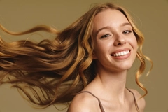 Image A woman smiling as her hair blows behind her.