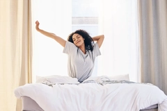 Morning stretching, black woman and wake up in home bedroom after sleeping or resting. 