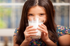 Young girl drinking a glass of milk indoors