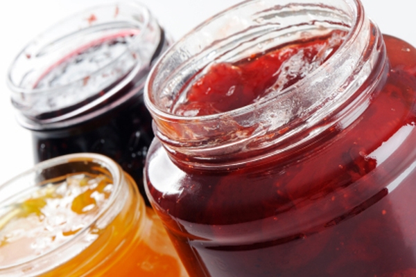 Image Open jars of assorted fruit jams in red, orange, and dark purple colors