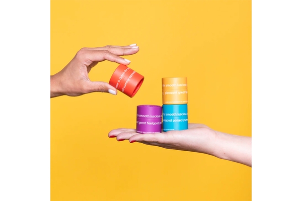 Image Two hands holding various vibrant lip balm containers.